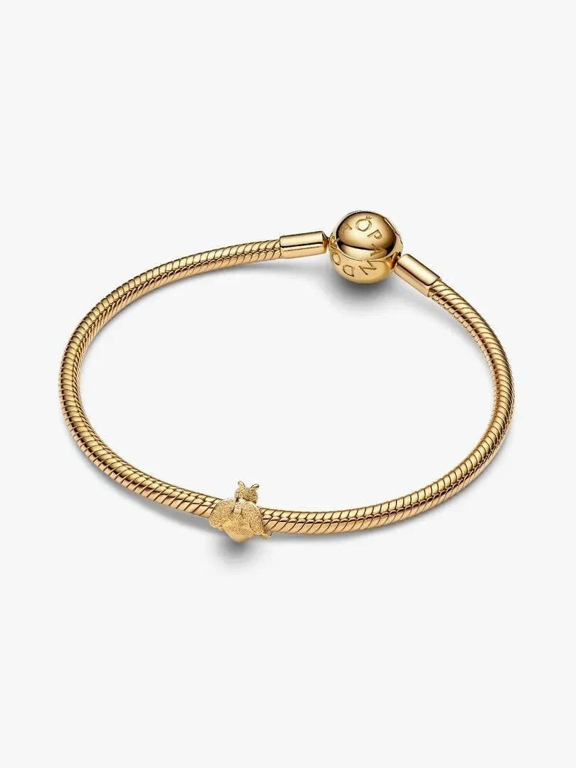 Bij charm aan een gouden armband, vooraanzicht onder een hoek, op witte achtergrond.