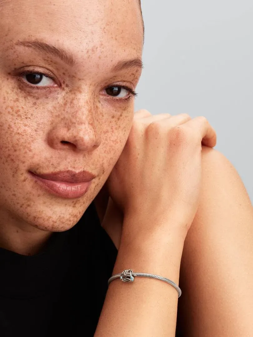 Close-up van de zeilboot charm om een pols, zijaanzicht op een model met neutrale achtergrond.