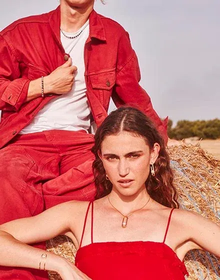 Modèle portant un collier et un bracelet, plan moyen en extérieur avec lumière naturelle et fond flou.