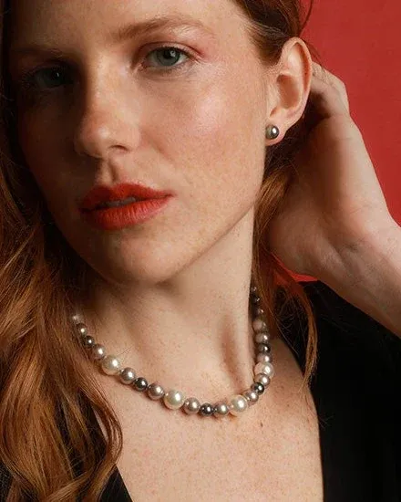 Primer plano de modelo con collar de perlas multicolor y pendientes a juego, fondo rojo vibrante.