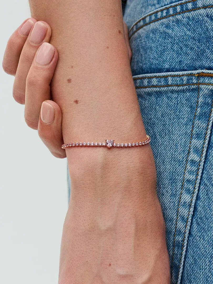 Close-up of the pink crystal bracelet on a wrist, positioned against blue denim fabric.