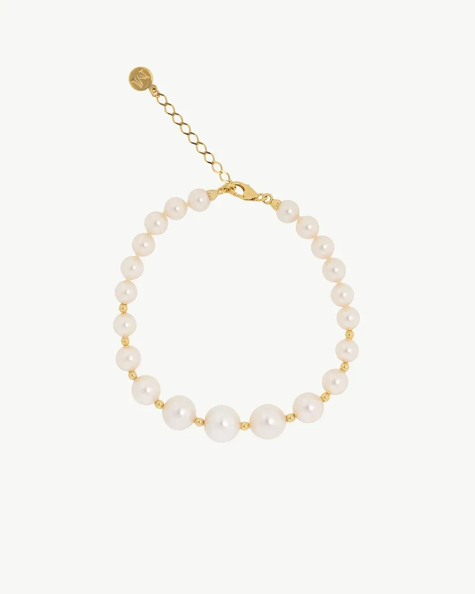 Pulsera de perlas dispuesta en círculo sobre fondo blanco, vista cenital con detalle del cierre y cadena de extensión.