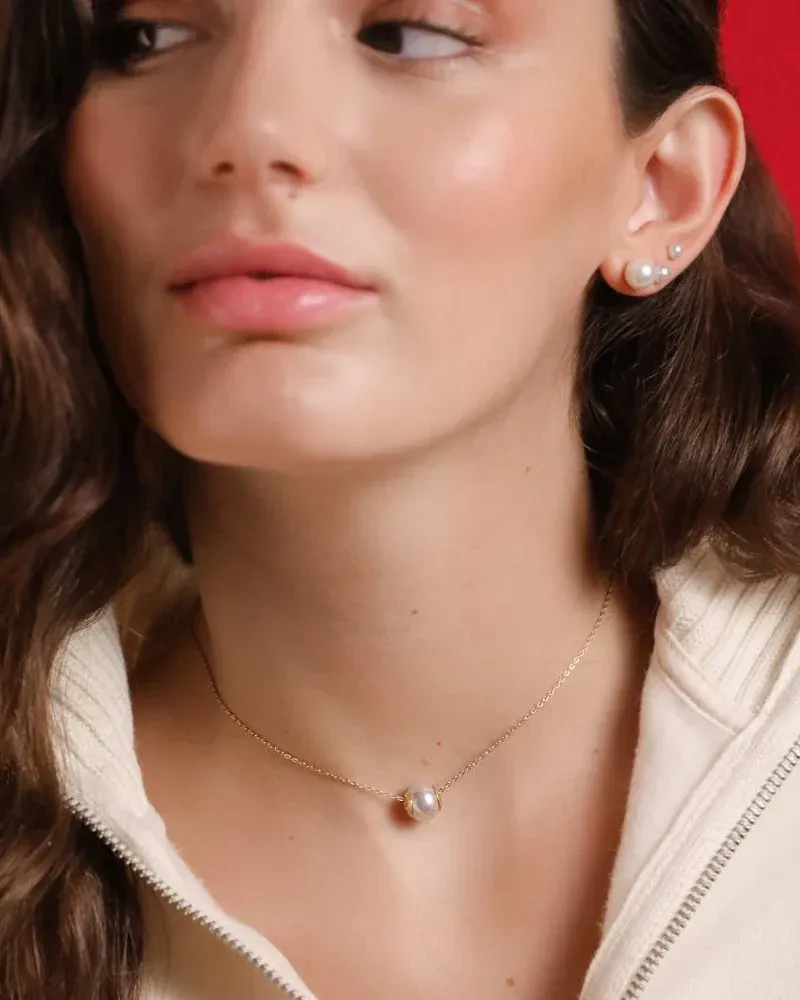 Close-up van parelketting om de hals van een model, levendig rode achtergrond, vooraanzicht.