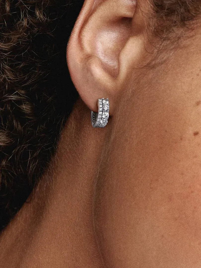 Zijaanzicht close-up van een dubbele band pavé oorring gedragen aan een oorlel, wazige achtergrond.