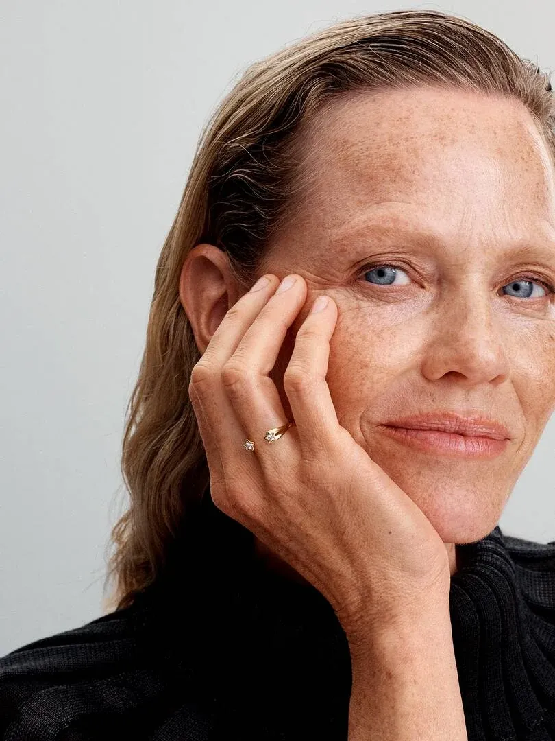 Nahaufnahme einer Hand am Gesicht, die den goldenen Ring mit Zirkonia am Mittelfinger zeigt.