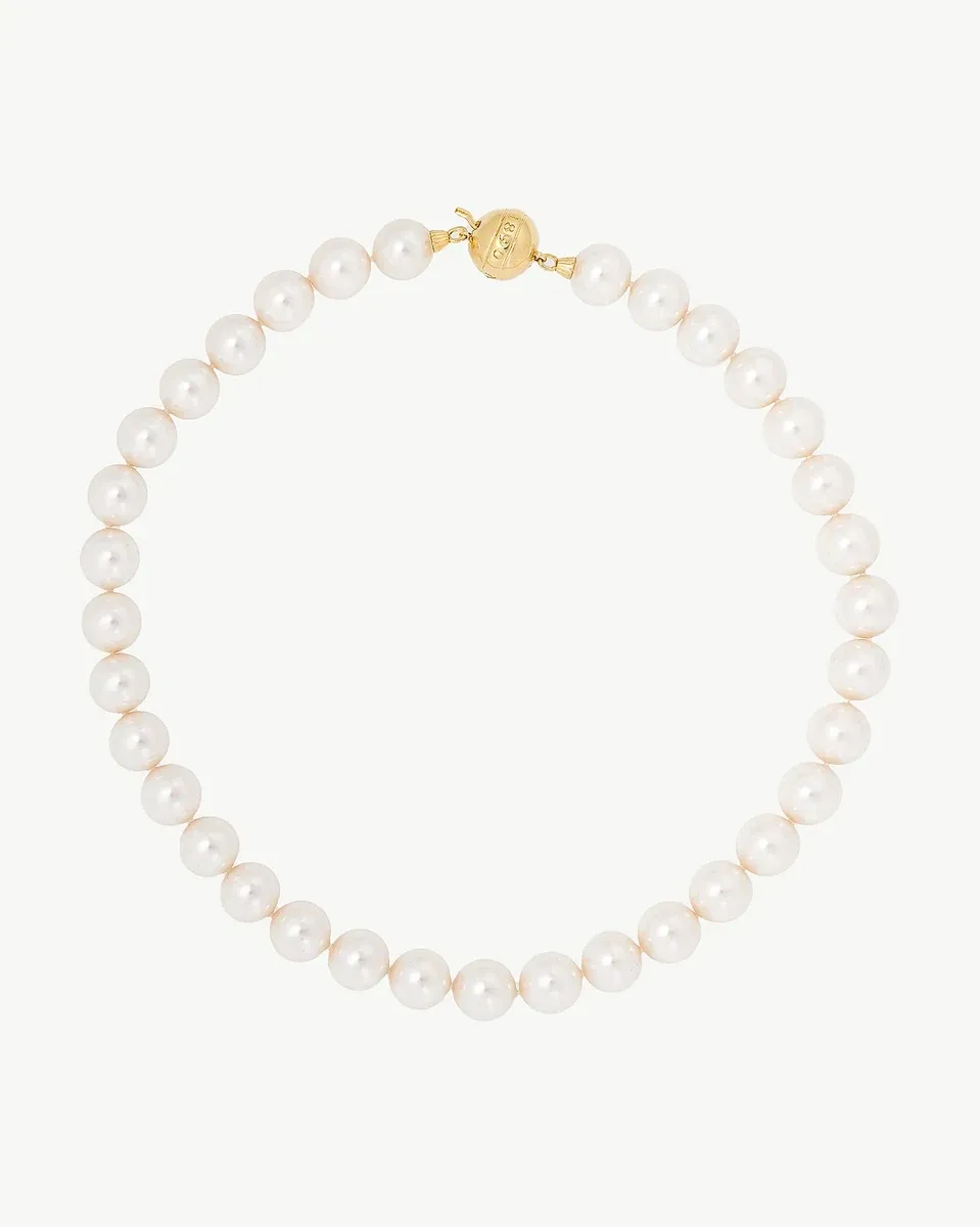 Collar de perlas dispuesto en círculo sobre fondo blanco, vista frontal con cierre dorado visible.