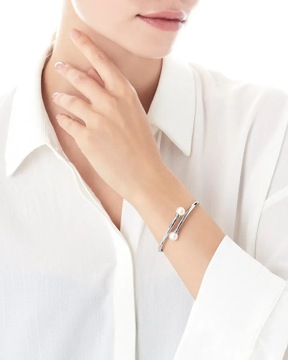 Brazalete puesto en la muñeca de una modelo con camisa blanca, fondo luminoso, plano medio corto.
