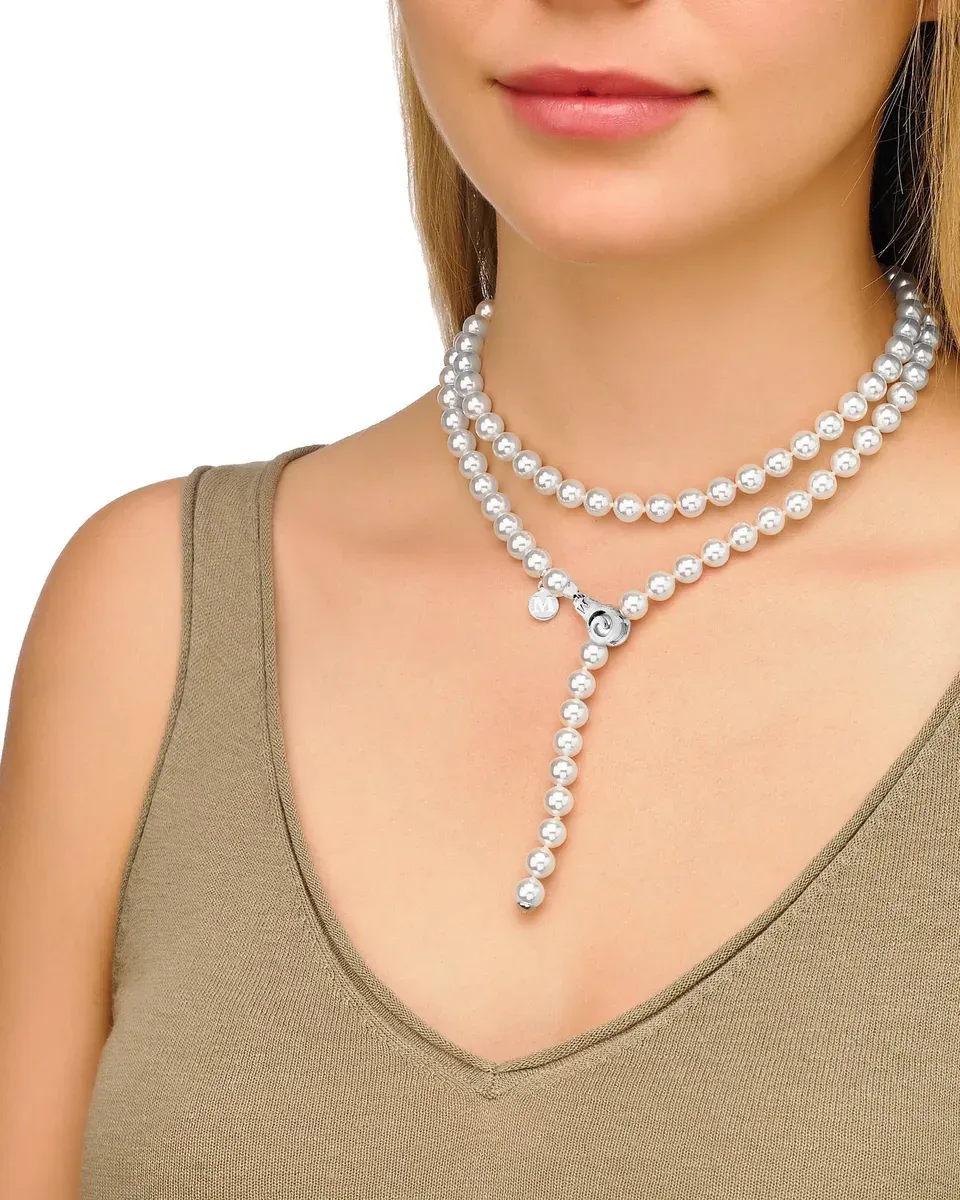 Primer plano del collar de perlas sobre el cuello y escote de una modelo, toma frontal con fondo blanco.