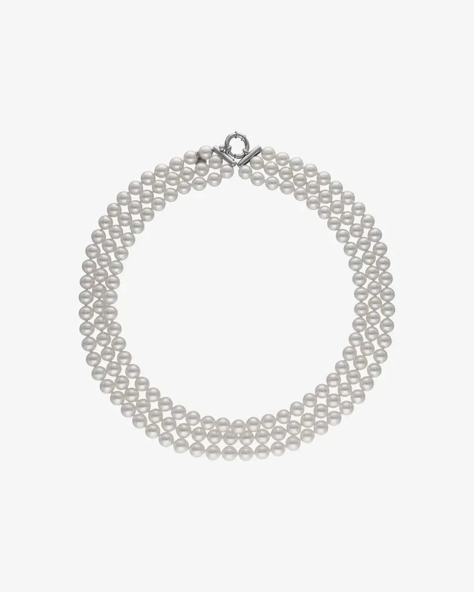 Three-strand white pearl necklace arranged in a circle on a white background, top view.