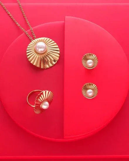 Set van ketting, oorbellen en ring op een rode ronde basis met geometrische compositie.