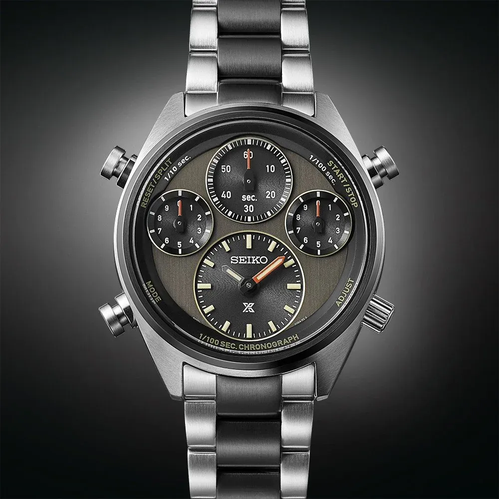 Vista frontal completa del reloj sobre fondo degradado oscuro, mostrando la esfera y el brazalete de acero.