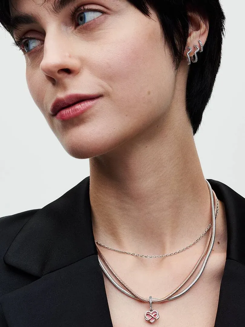 Close-up of double chain necklace with rose gold pendant worn on model's neck, neutral background.
