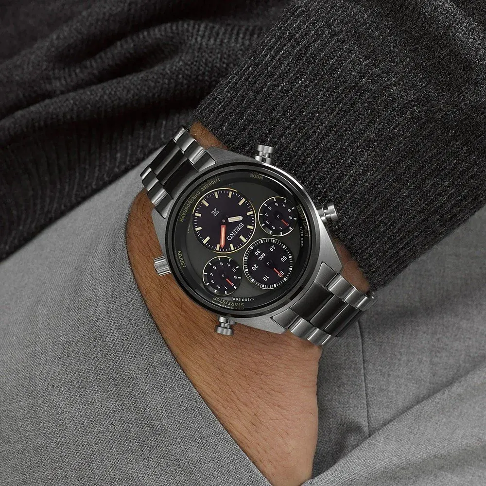 Reloj puesto en muñeca, toma en primer plano sobre fondo de tejido gris texturizado.