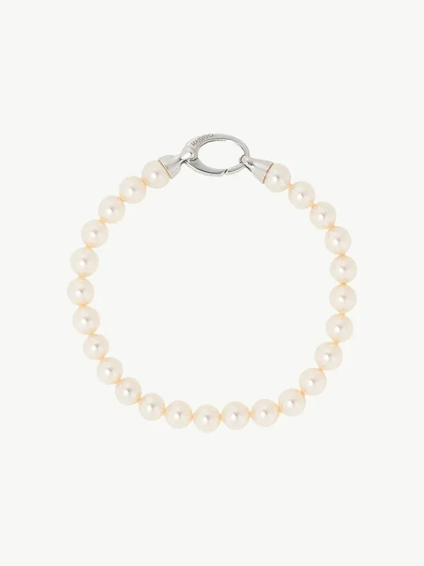 Pulsera de perlas dispuesta en círculo sobre fondo blanco, vista cenital con detalle del cierre de plata.