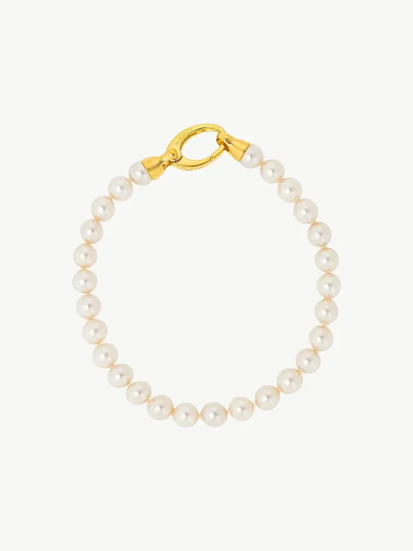 Pulsera de perlas dispuesta en círculo sobre fondo blanco, vista cenital con detalle del cierre dorado.