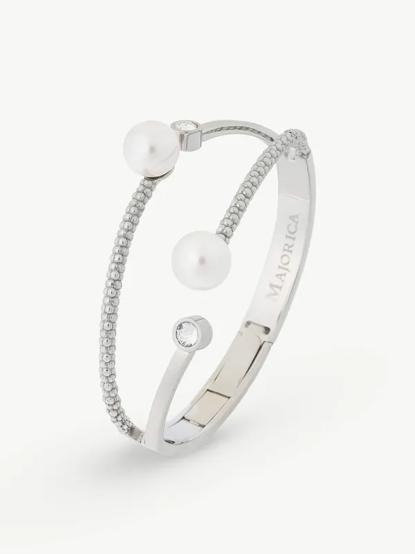 Vista en perspectiva de brazalete rígido con perlas y circonitas sobre fondo blanco