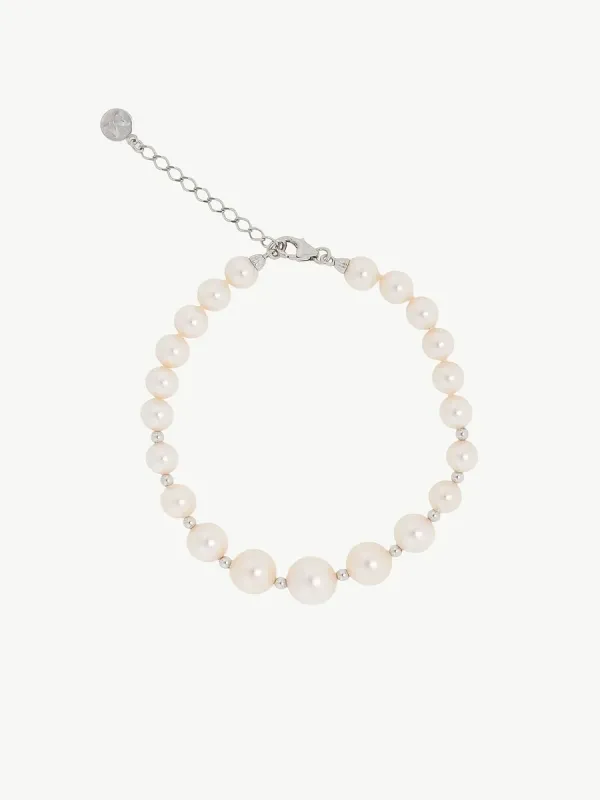 Vista cenital de pulsera de perlas dispuesta en círculo sobre fondo blanco, incluyendo el cierre de cadena de plata