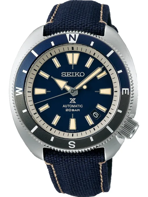 Vista frontal del reloj con esfera azul y bisel bicolor, correa de tejido azul, sobre fondo blanco
