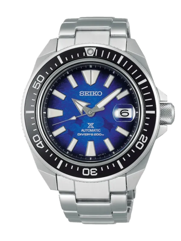 Vista frontal del reloj, esfera azul con motivo texturizado, bisel rotatorio negro y brazalete de acero, fondo blanco.