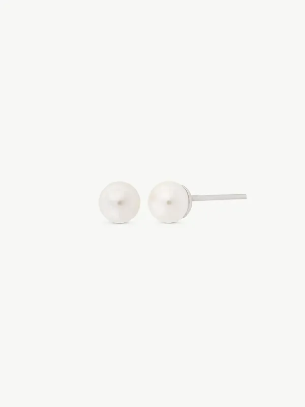 Pendientes de perla blanca sobre fondo blanco, vista frontal y lateral con detalle del cierre de pincho.