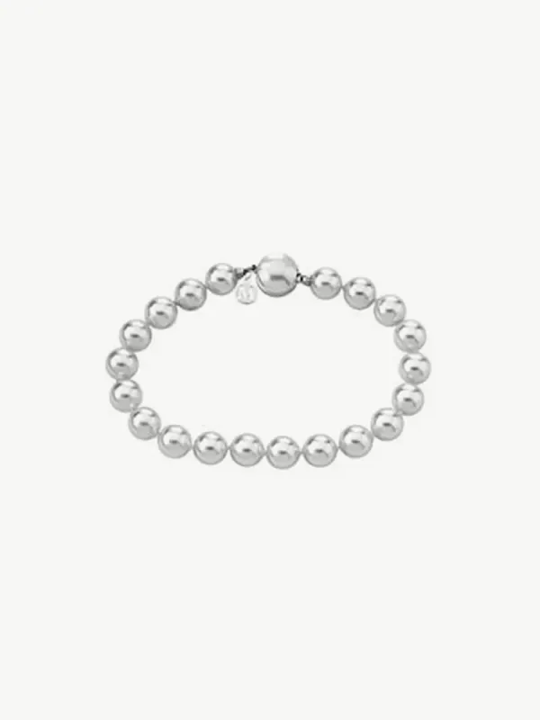 Pulsera de perlas dispuesta en círculo sobre fondo blanco, vista cenital.