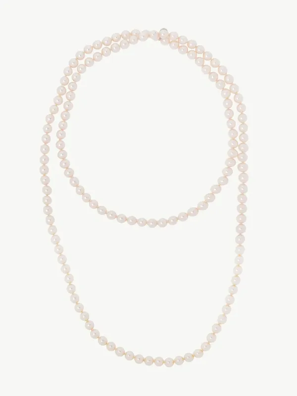Vista cenital de collar de perlas blancas dispuesto en doble vuelta sobre fondo blanco