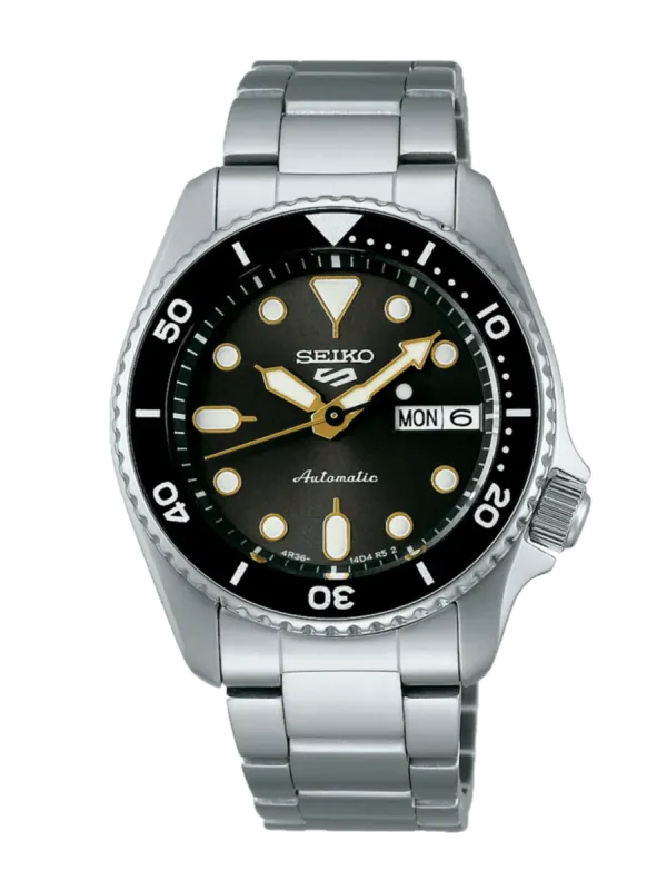 Vista frontal completa del reloj con brazalete de acero, esfera negra y bisel rotatorio sobre fondo blanco.