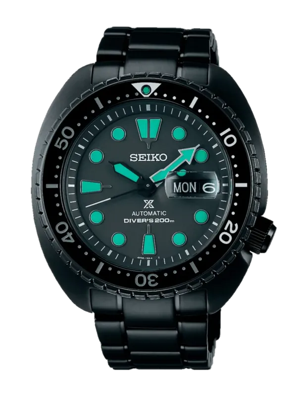 Vista frontal completa de reloj negro con índices luminiscentes verdes sobre fondo blanco.
