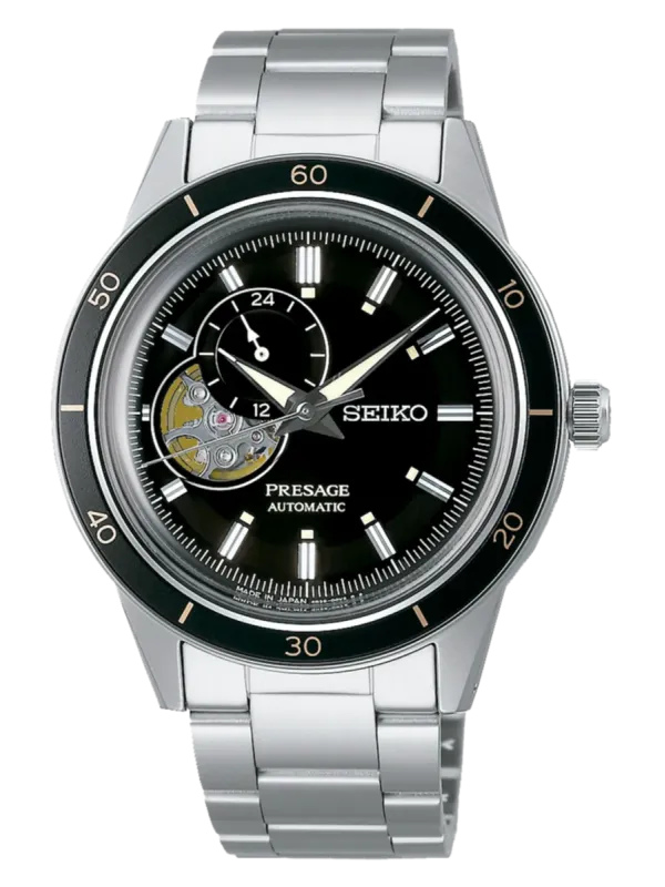 Vista frontal completa del reloj, esfera negra con maquinaria vista y brazalete de acero, fondo blanco.