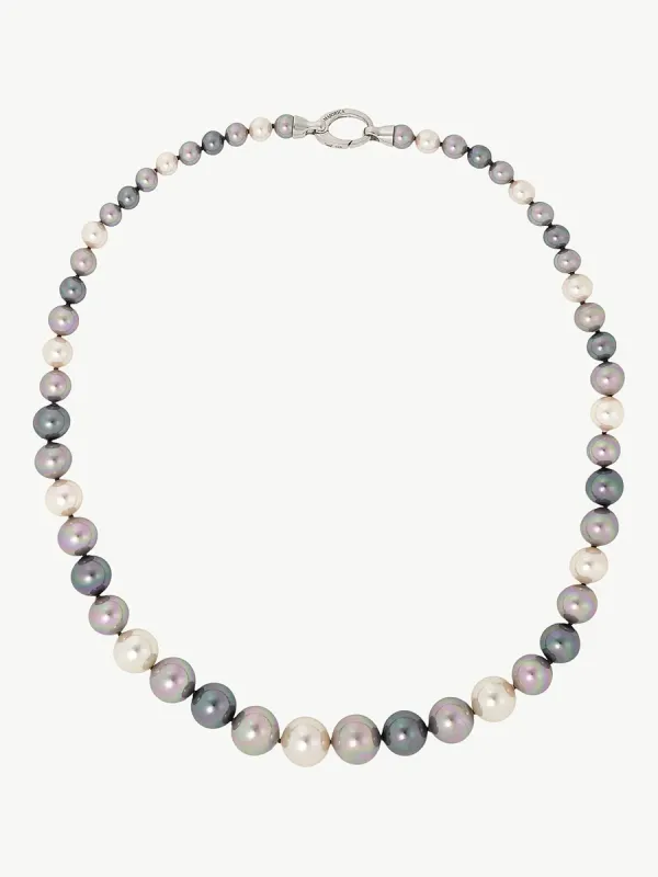 Collar de perlas multicolor dispuesto en círculo sobre fondo blanco, vista cenital con cierre de plata visible.