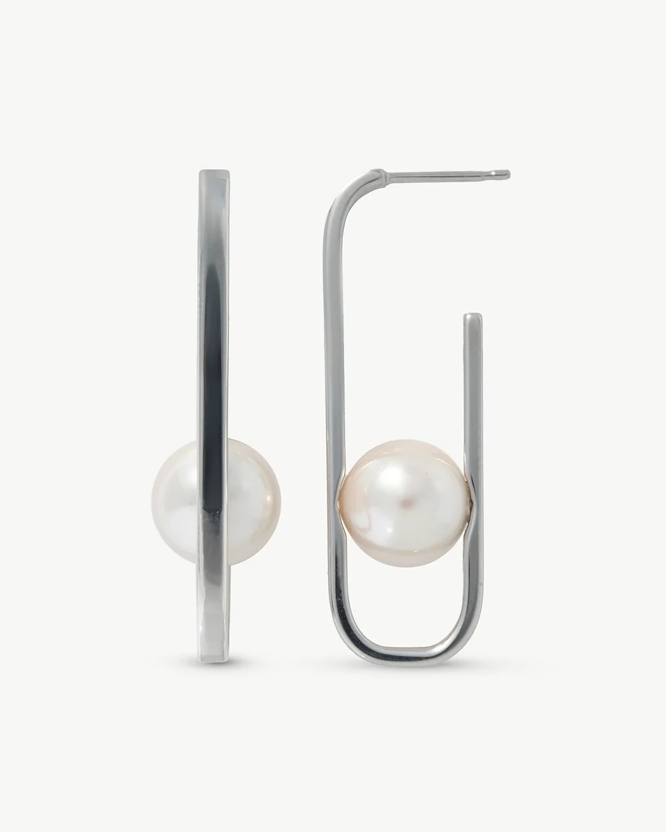 Vista frontal y de perfil de pendientes de perla blanca con estructura ovalada de plata sobre fondo blanco.