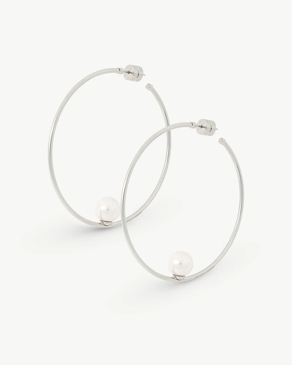 Boucles d'oreilles créoles avec perle blanche, vue de face inclinée, sur fond blanc pur.