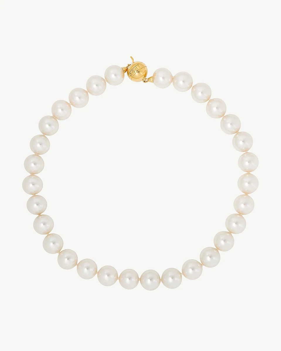 Collier de perles disposé en cercle sur fond blanc, vue de face avec fermoir doré visible.