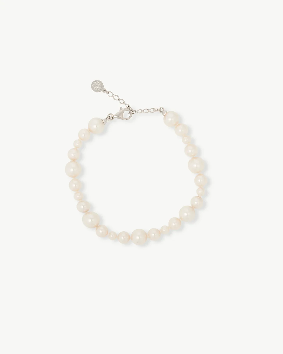 Vista superior de la pulsera circular sobre fondo blanco, mostrando el cierre y las perlas en degradado.