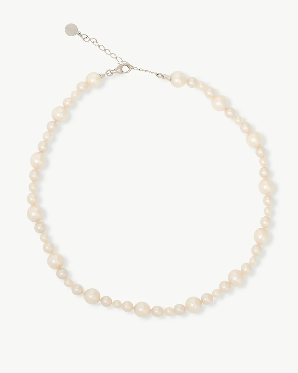 Collier de perles disposé en cercle sur fond blanc, vue de face avec fermoir en argent visible.
