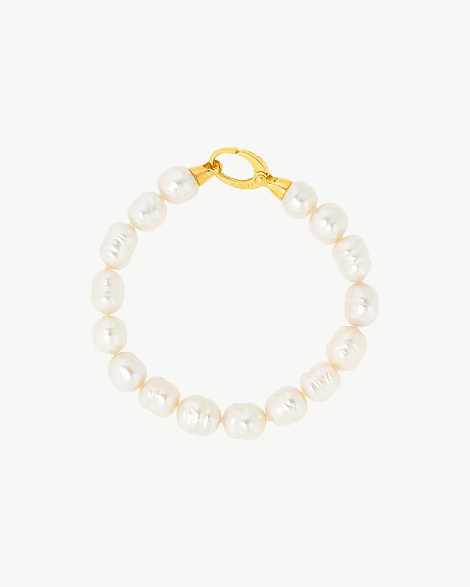 Top view of a bracelet arranged in a circle on a white background, detail of the gold clasp.