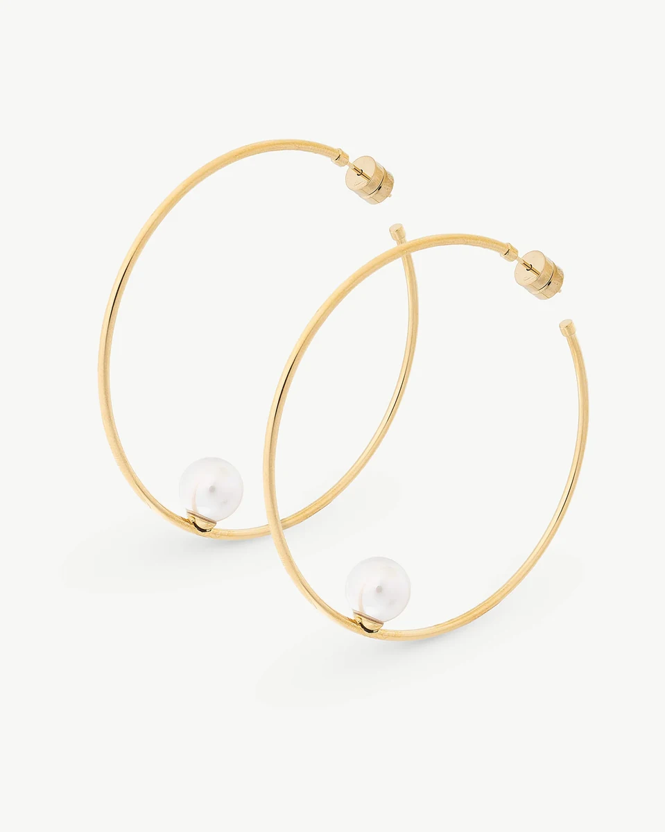 Paire de créoles dorés avec perle blanche, vue de face sur fond blanc.