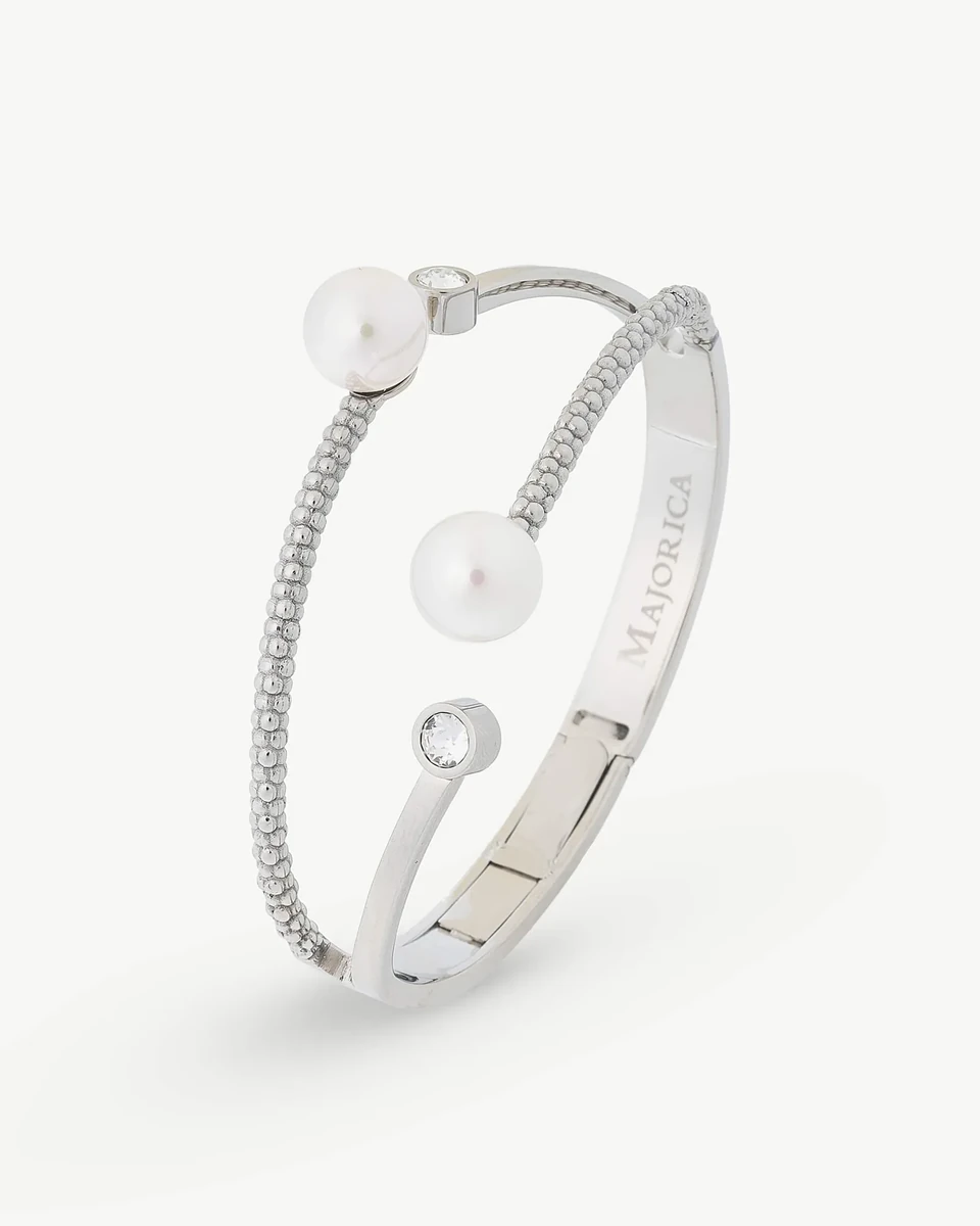 Vista en perspectiva de brazalete rígido con perlas y circonitas sobre fondo blanco