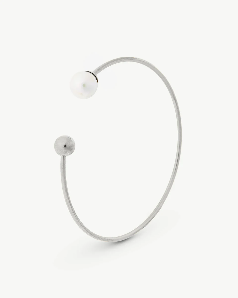 Bracelet en acier vu de profil sur fond blanc, mettant en valeur la perle et le fermoir sphérique.