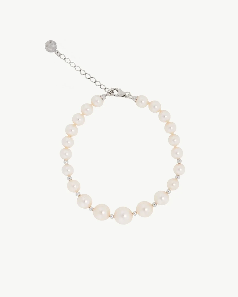 Vista cenital de pulsera de perlas dispuesta en círculo sobre fondo blanco, incluyendo el cierre de cadena de plata