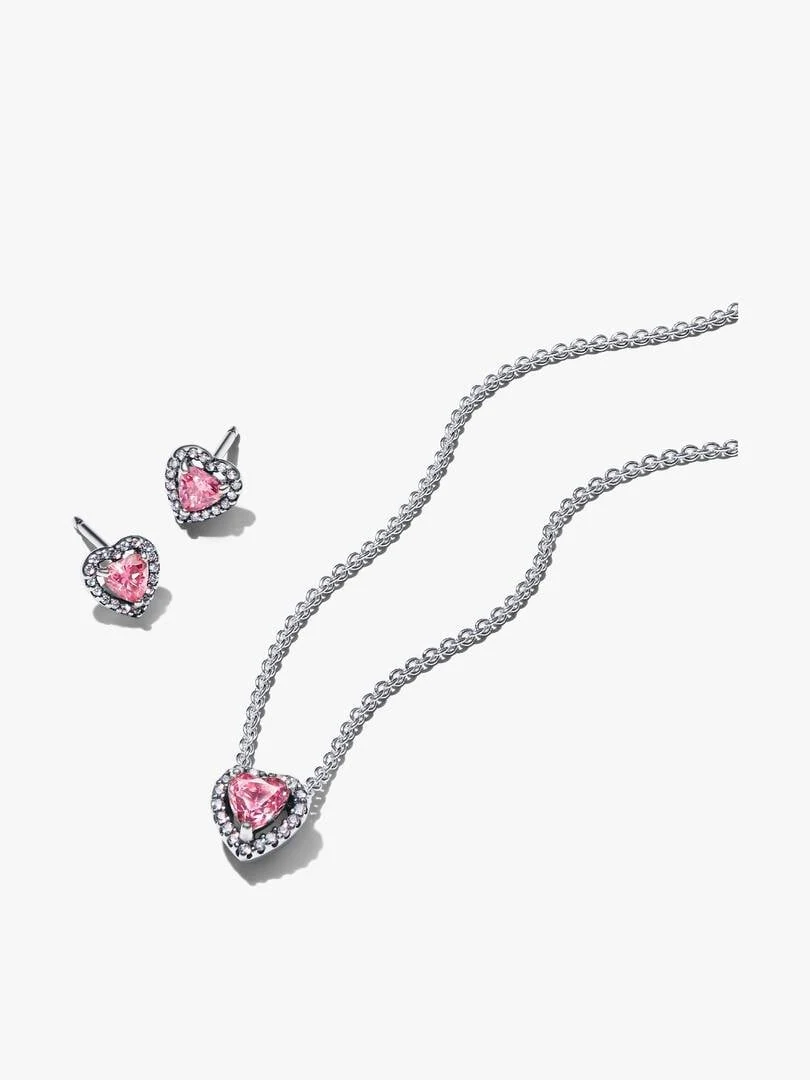 Conjunto de collar y pendientes de corazón rosa sobre fondo blanco, toma cenital con disposición diagonal.