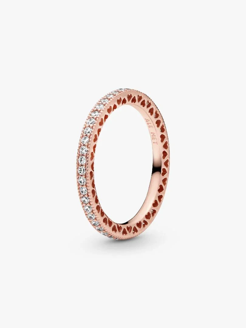 Rose gold ring shown from a side angle, white background, detail of heart pattern and cubic zirconia.