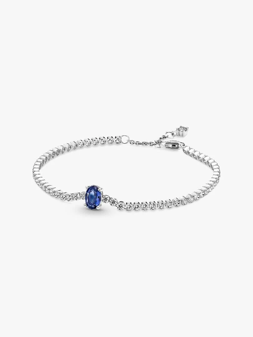 Pulsera de plata con cristal azul ovalado sobre fondo blanco, vista frontal en ángulo.