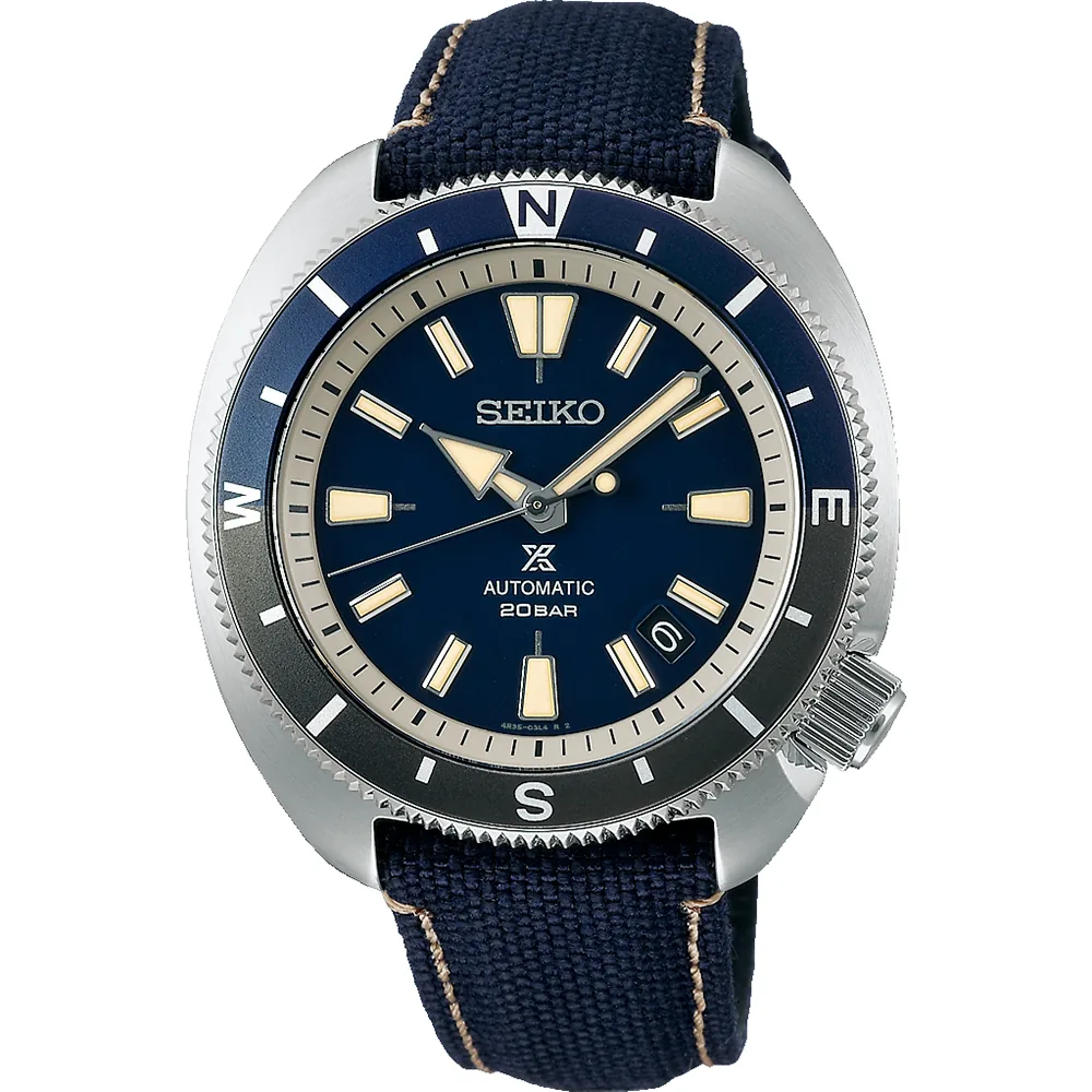 Vista frontal del reloj con esfera azul y bisel bicolor, correa de tejido azul, sobre fondo blanco