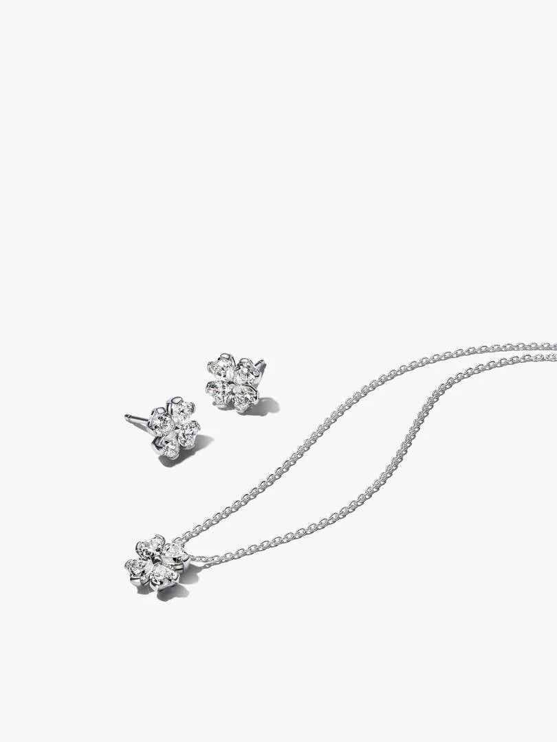 Collar y pendientes de trébol con circonitas sobre fondo blanco, vista superior diagonal.
