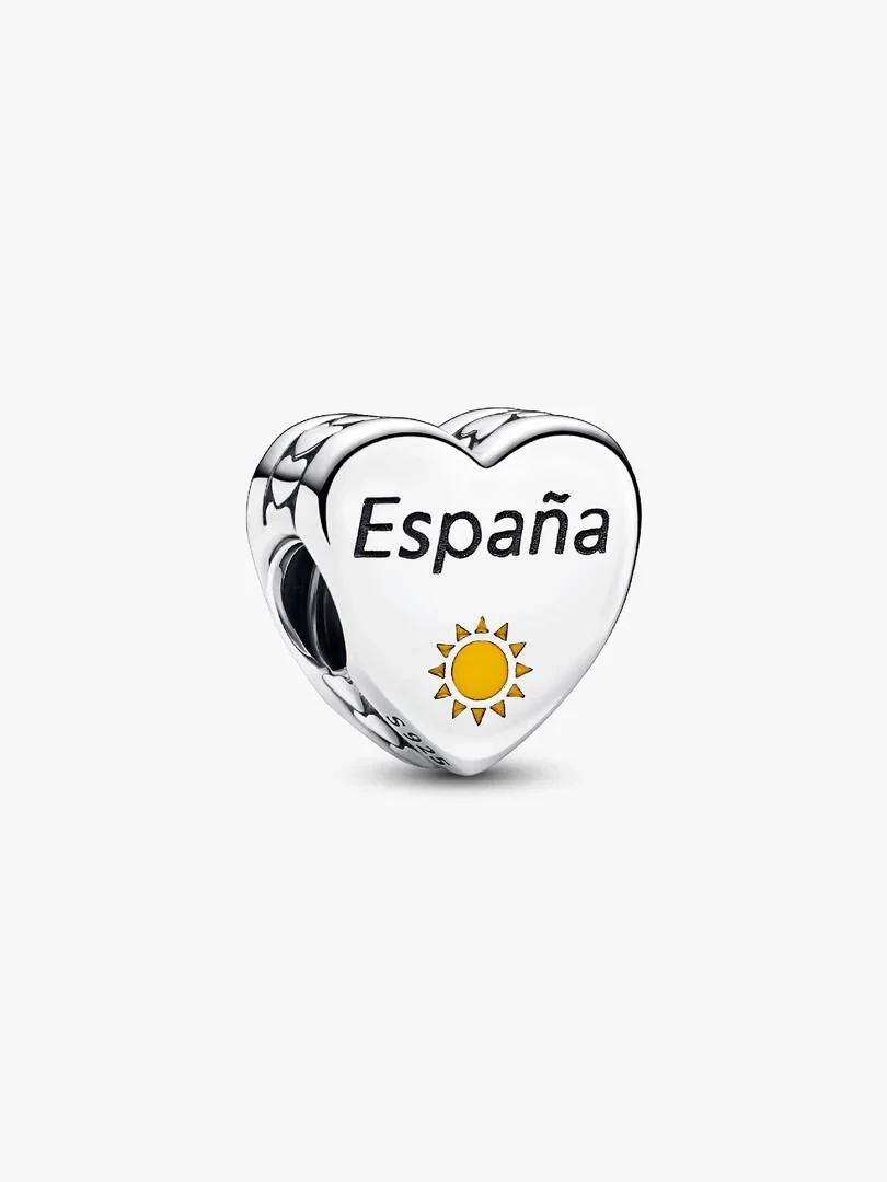 Charm de corazón en plata con grabado 'España' y sol esmaltado, vista frontal en ángulo sobre fondo blanco.