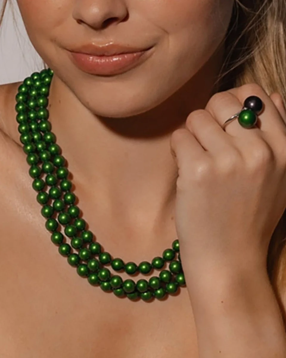 Gros plan du collier à trois rangs sur le cou d'un mannequin, vue de face avec la main près du visage.