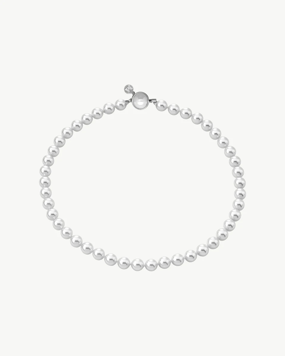 Pearl necklace arranged in a circular shape on a white background, top view showing the silver clasp.
