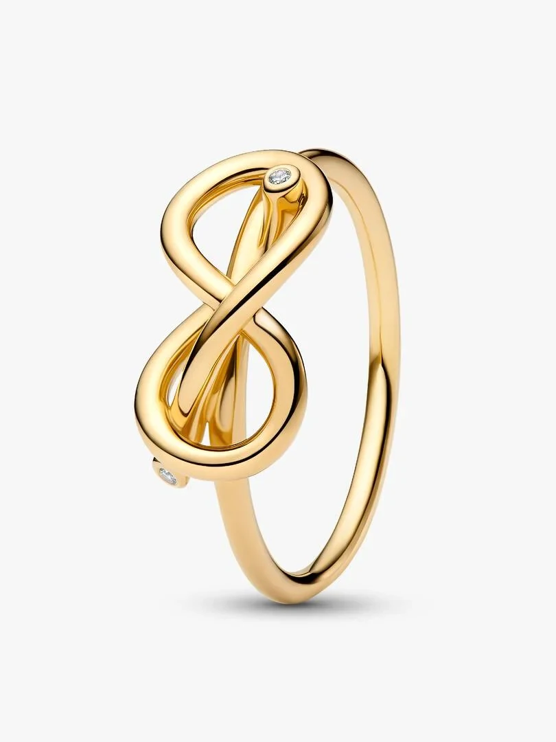 Anillo de nudo infinito en oro de 14k con circonitas, vista lateral sobre fondo blanco.