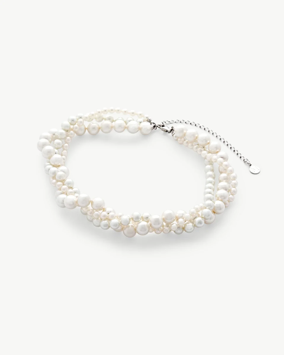 Triple strand white pearl necklace arranged in a circle on a white background, front view.